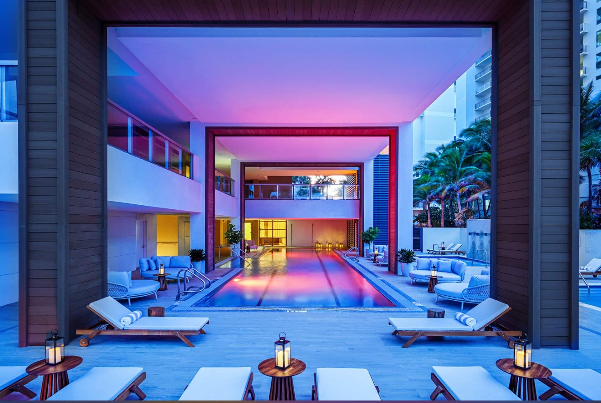 The pool deck after dark, lit in warm and magenta light