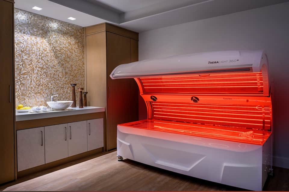Red light therapy bed glowing in a private treatment room