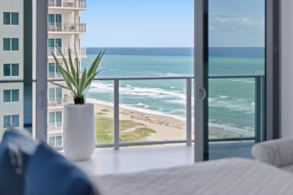 A bedroom corner opening to the balcony and the ocean beyond